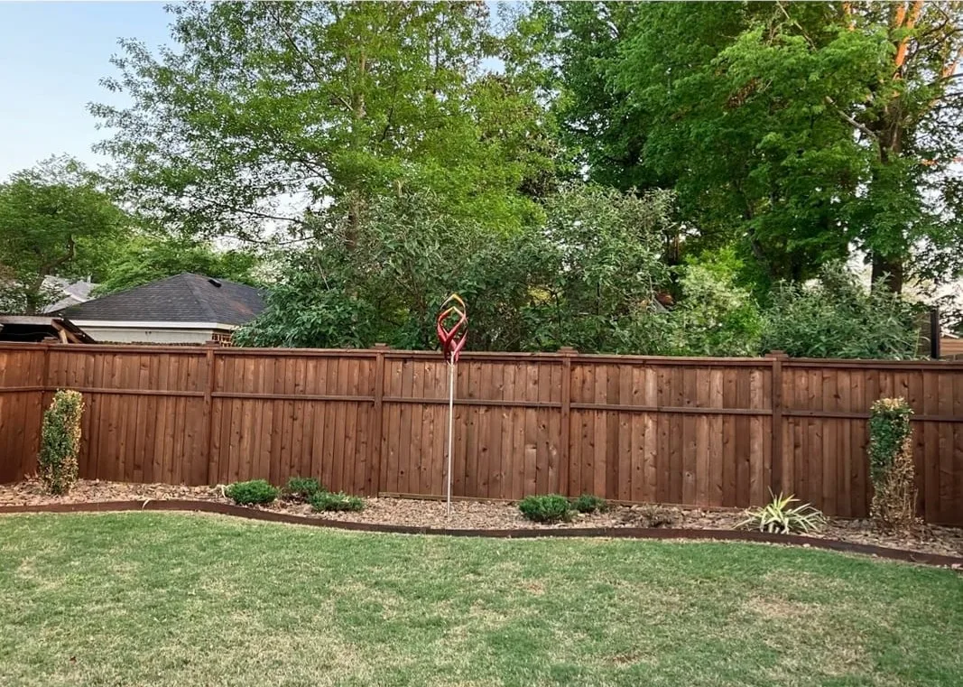 The same fence line after: an edged planting bed and an even lawn