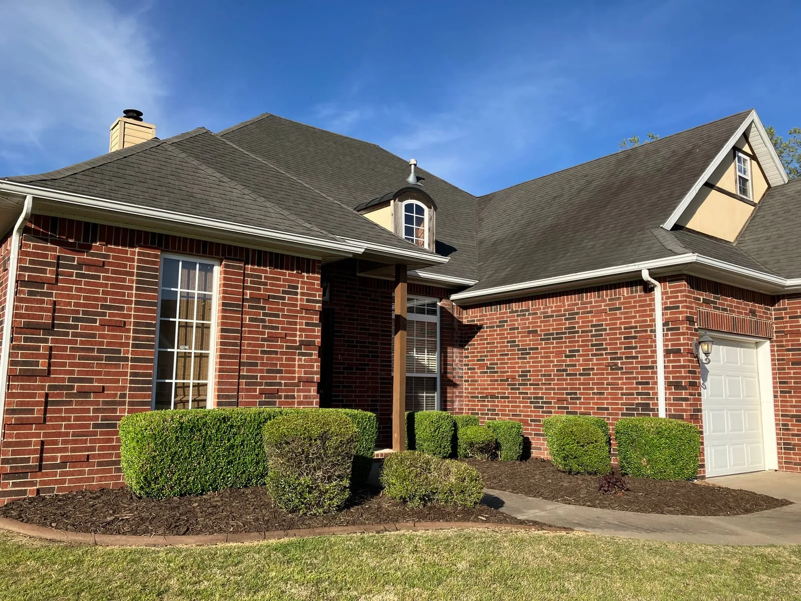 Brick home with neatly shaped hedges and fresh mulch beds along the front