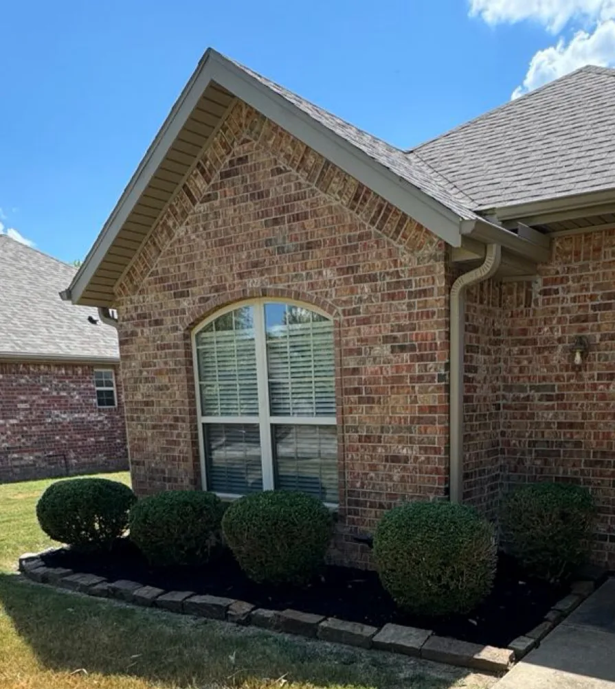 Brick home with rounded shrubs in a stone-edged, freshly mulched front bed